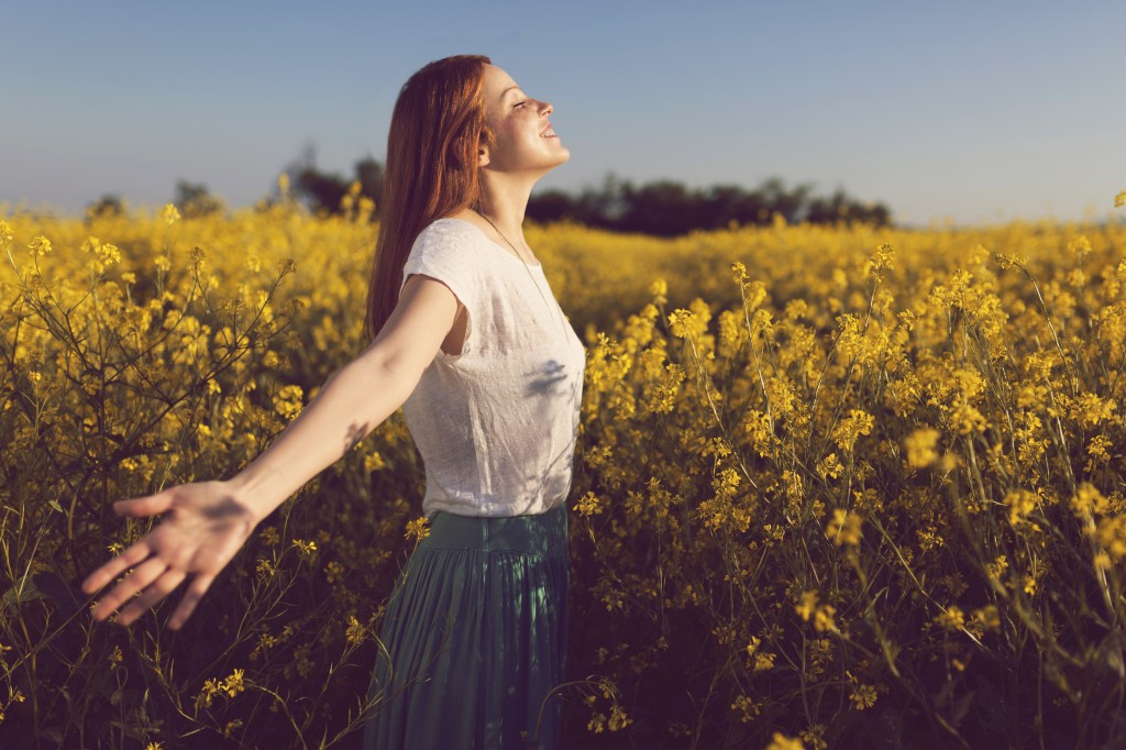 בחורה חופשייה עם זרועות ידיים פתוחו בדשה פרחים צהובים, אלופציה - יומן החלמה לירז